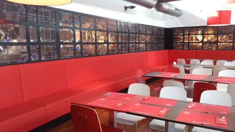 Kantine met rode banken en een wand met glaspanelen