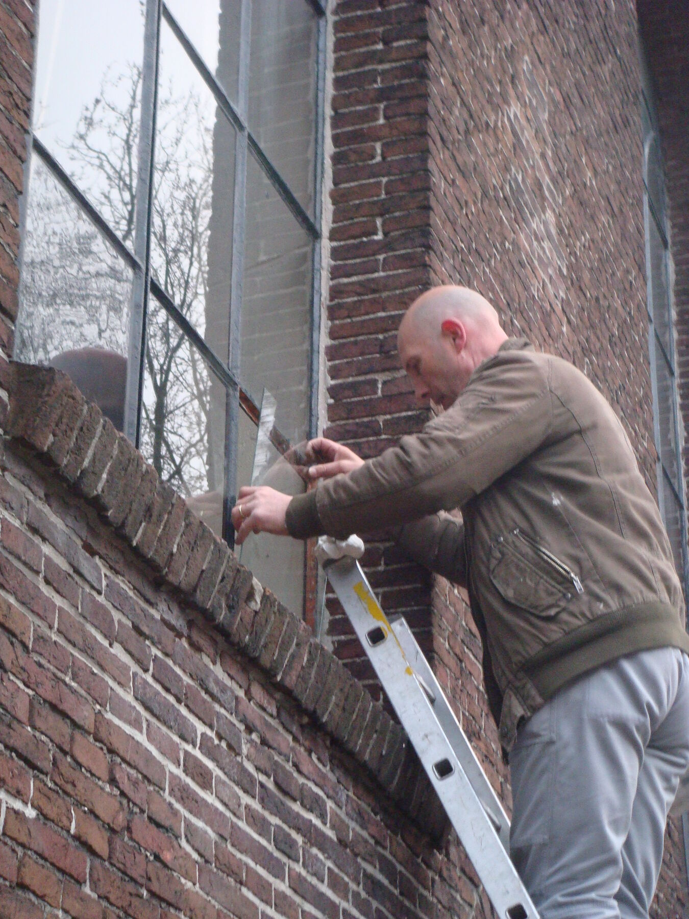 Monteur op een ladder bij een kerkraam